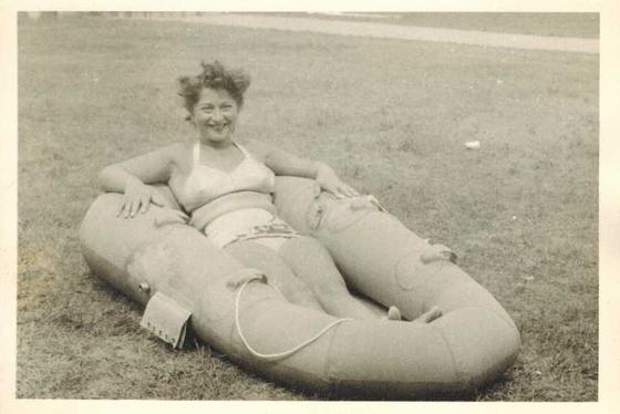 Mae in a bikini sitting in an inflatable raft on the grass.