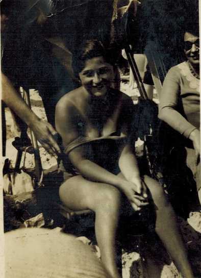 A woman sitting on a beach, smiling.