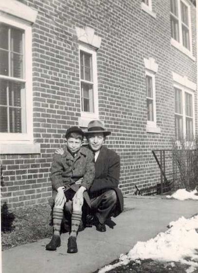 Harold with his son Warren, in front of a brick building after a snow.