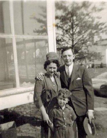 Harold and Mae with their son Warren, small, in front of a house.