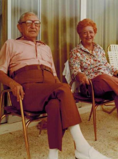 Harold and Mae sitting side by side on a patio in metal lawn chairs.