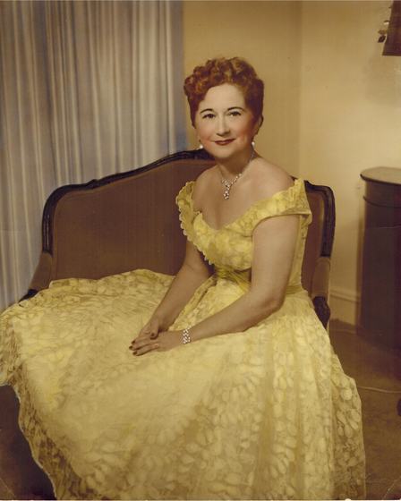 Mae in a yellow lace gown, in a hand-tinted studio portrait.