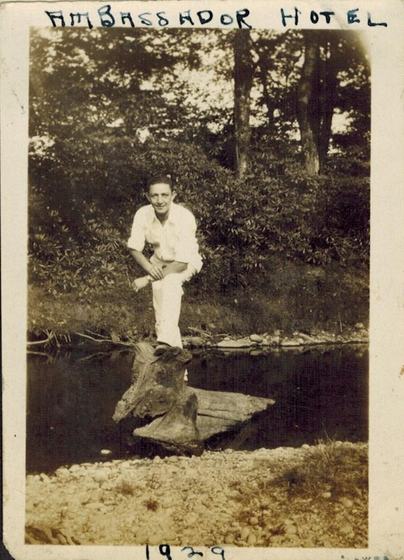 Harold, a young man standing on a log at the edge of a pond.