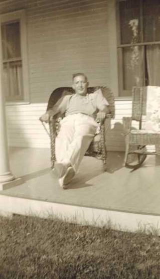 Harold relaxing in a wicker chair on a porch, with a second wicker chair beside him.