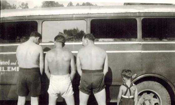 Harold, Tootsie and a friend, shirtless, and Warren as a small boy, seen from behind at the side of a bus. The lettering reads "Owned and ... R. L. EME..." (the same bus as P115).